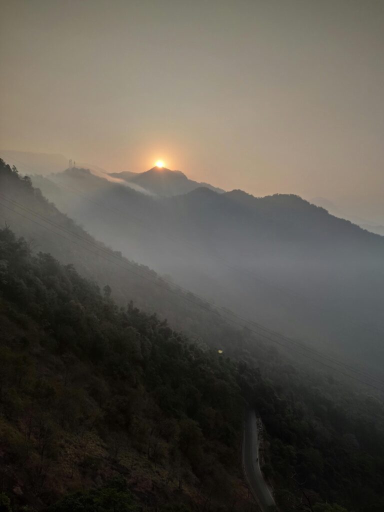 Serene sunset with mist over mountains in Wayanad, India.