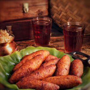 A delicious platter of Unnakai served with glasses of beverage, creating a mouth-watering Indian meal setting.