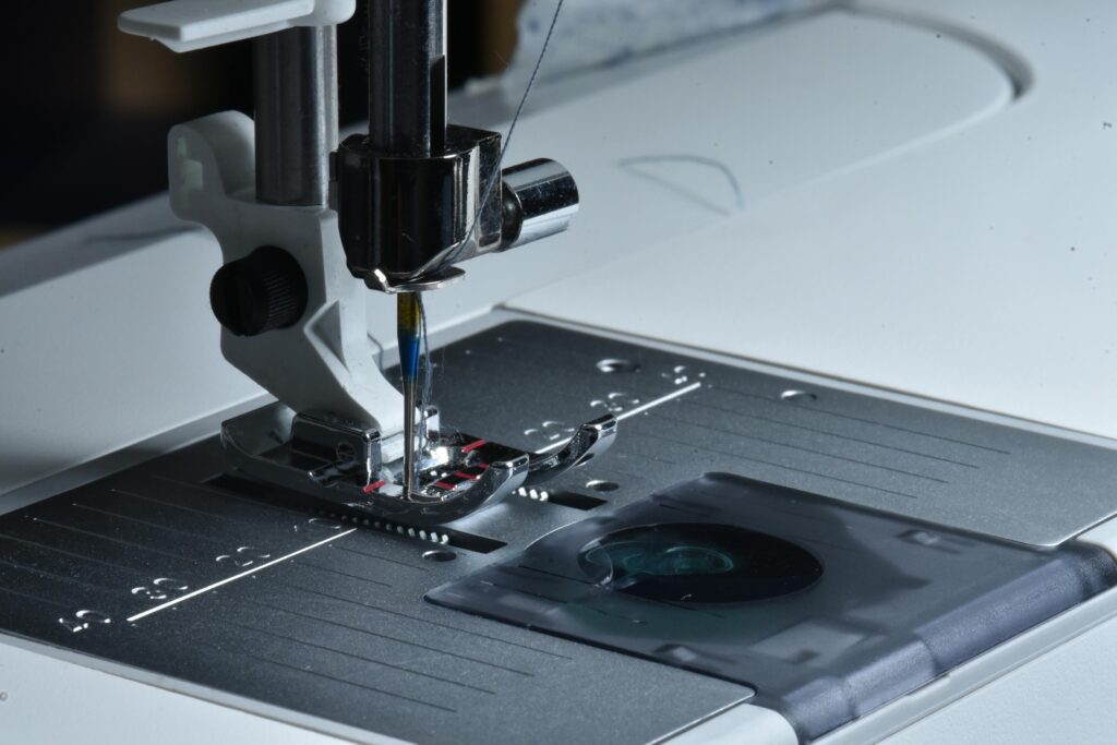 Detailed view of a sewing machine needle and presser foot on a sewing machine.